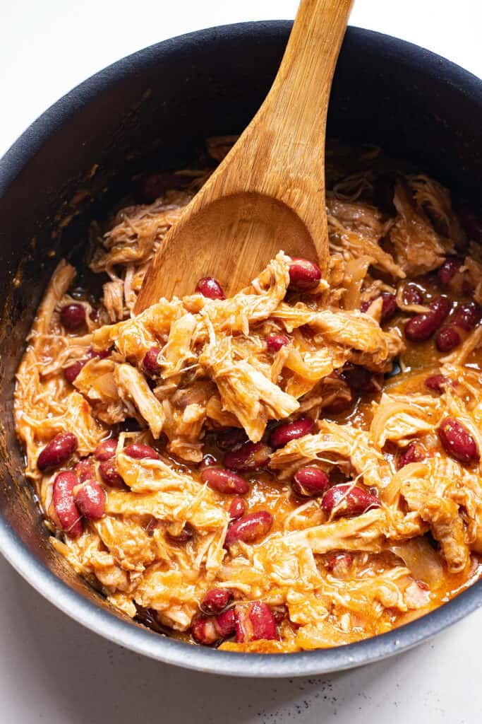 wooden spoon scooping pulled pork and beans