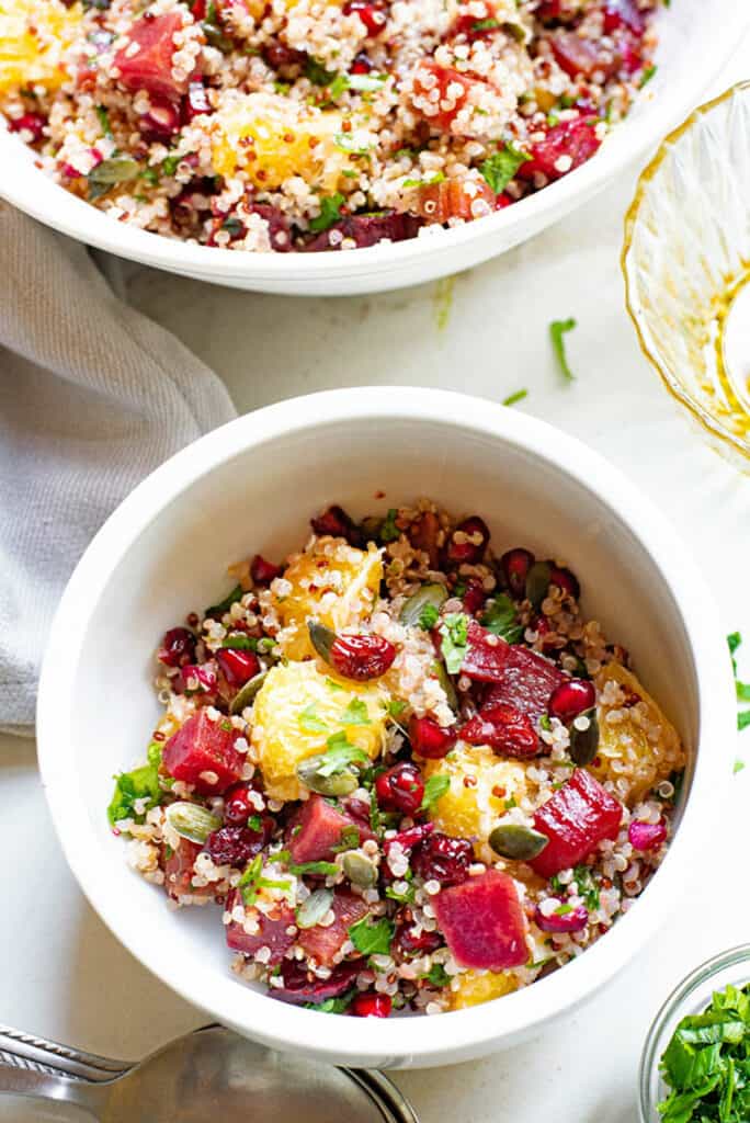 cup full of Beet & Orange Quinoa Salad on table with bowl