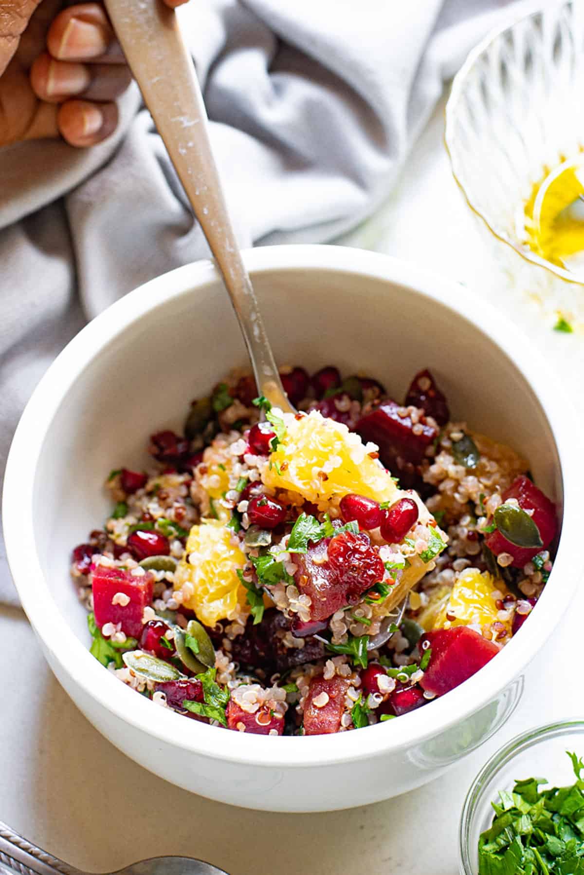 spoon scooping bite of orange and pomegranate quinoa salad