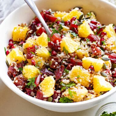 Beet & Orange Quinoa Salad with pomegranates in bowl with spoon