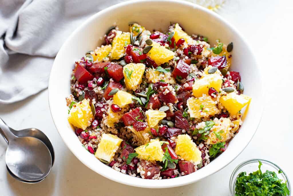 Beet & Orange Quinoa Salad with cranberries and pumpkin seeds in white bowl