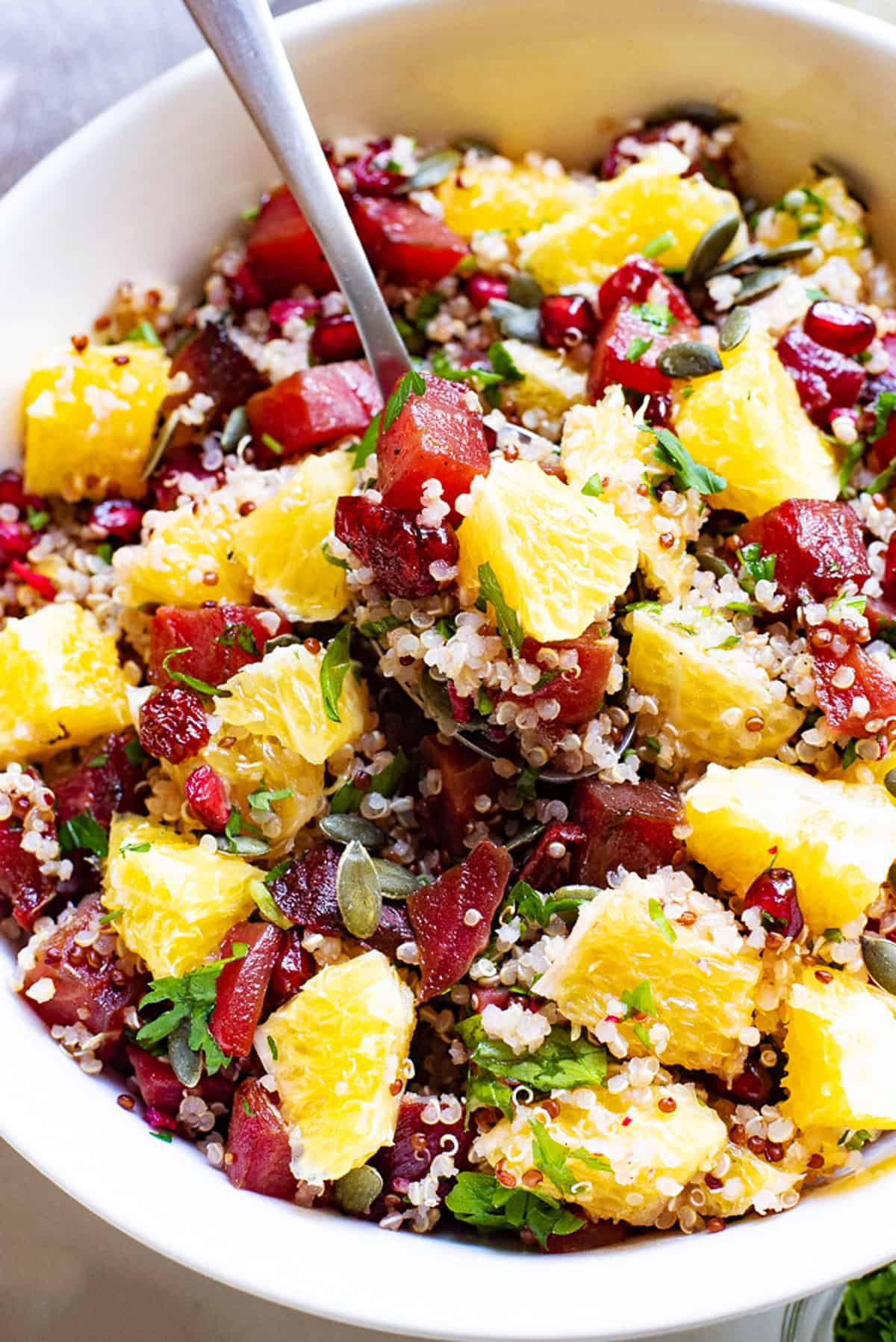 spoon scooping Beet & Orange Quinoa Salad with pomegranates and cranberries