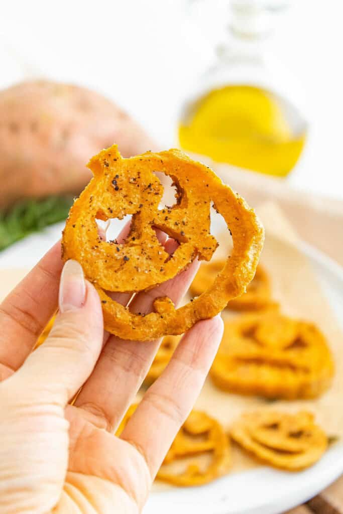 jack o lantern roasted sweet potato held in hand over plate