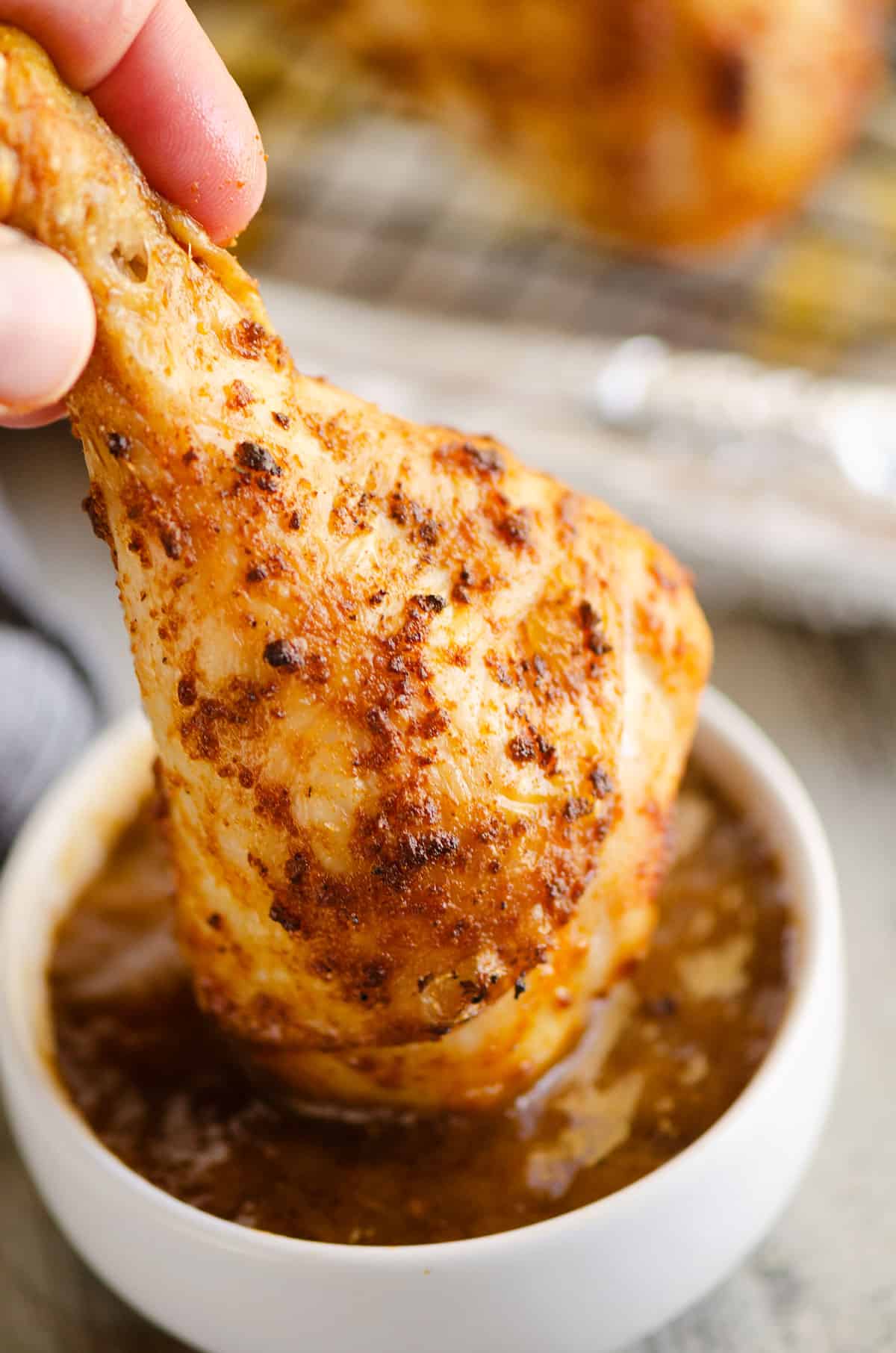 chicken leg dunked in cup of BBQ sauce