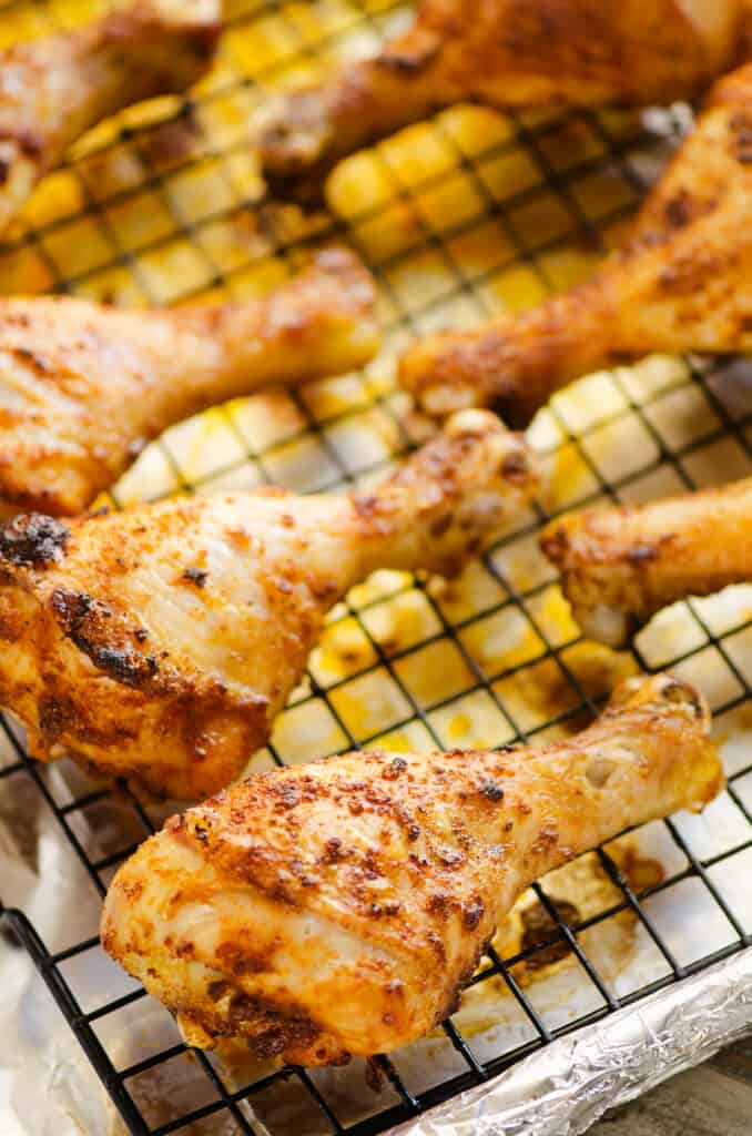 oven baked chicken legs on cookie sheet with cooling rack