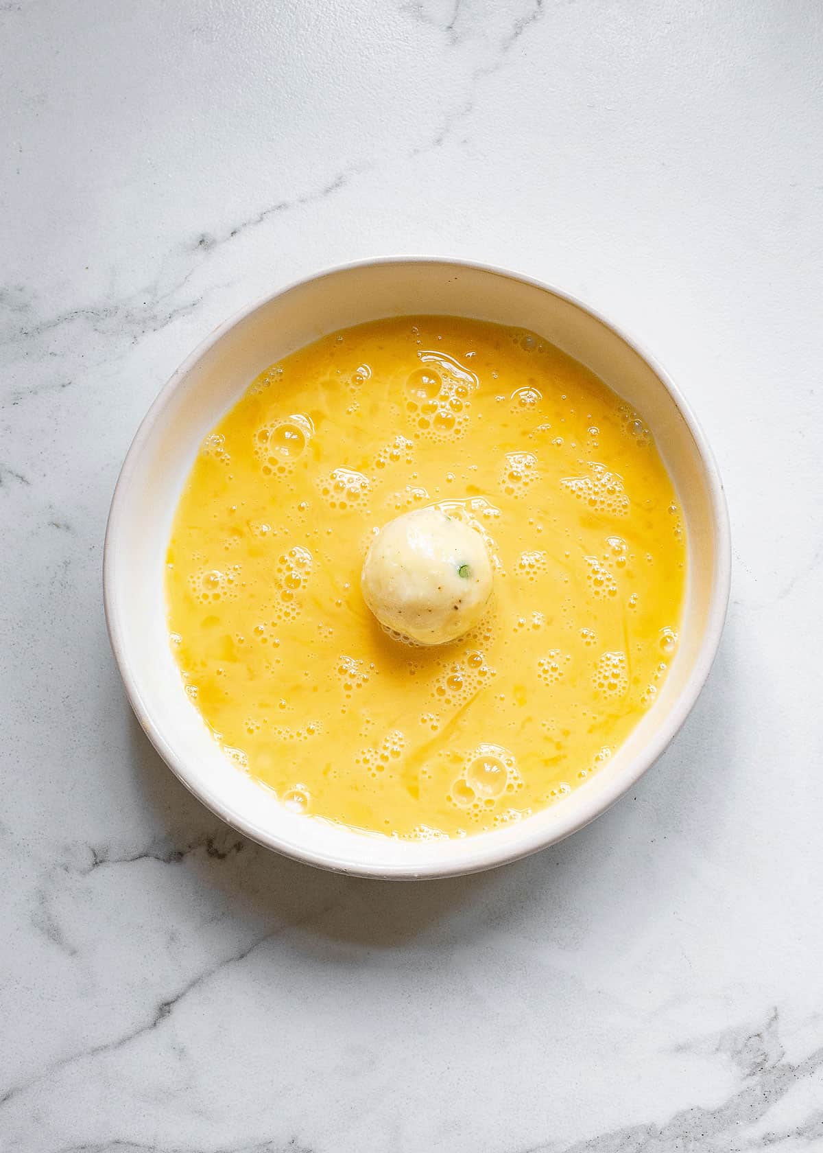 mashed potato ball on plate of egg wash