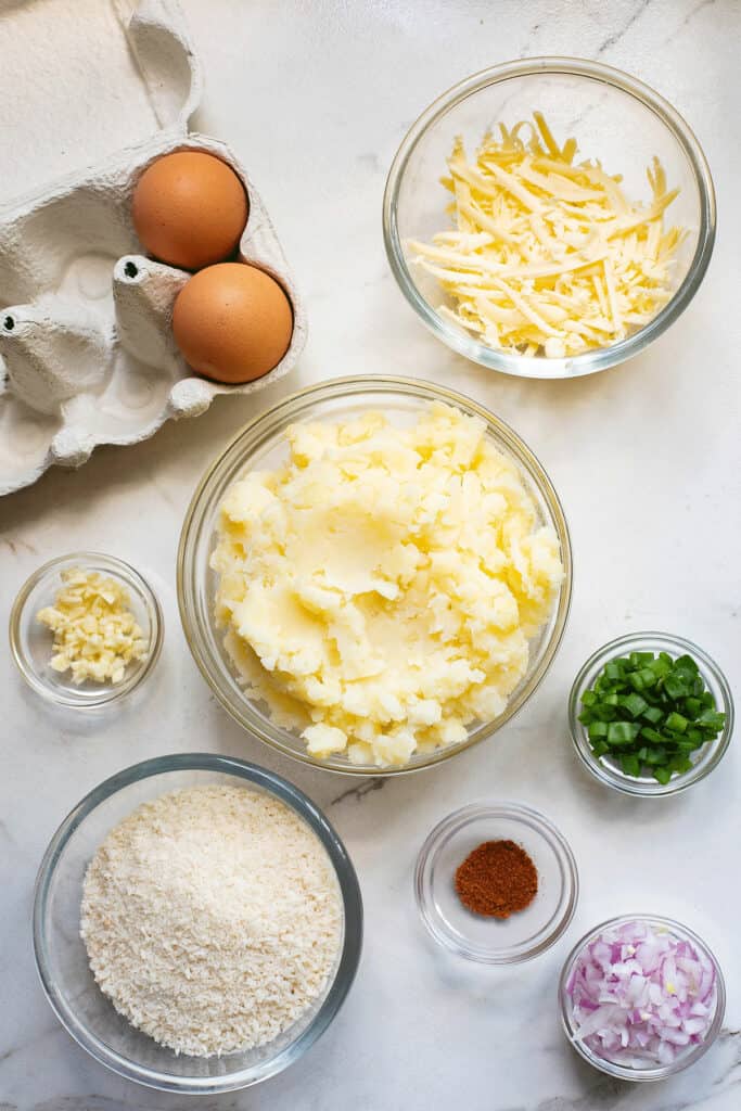mashed potatoes, cheese, chives, spices and eggs on table
