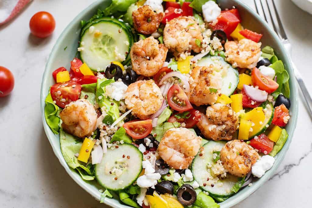 Mediterranean salad with shrimp and vegetables in bowl with fork