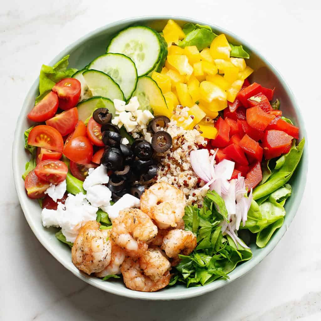 Mediterranean salad with shrimp and vegetables assembled in bowl