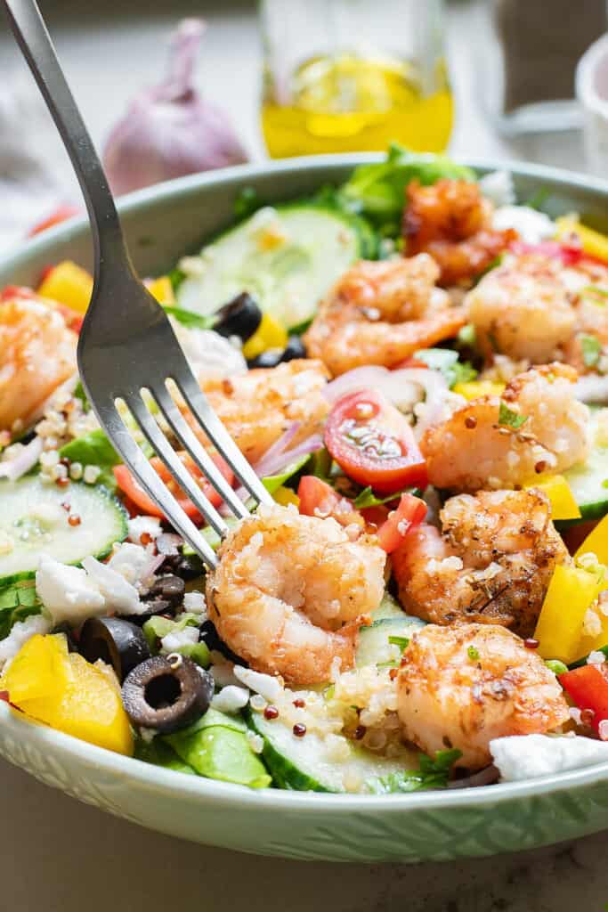 shrimp on fork in Greek salad