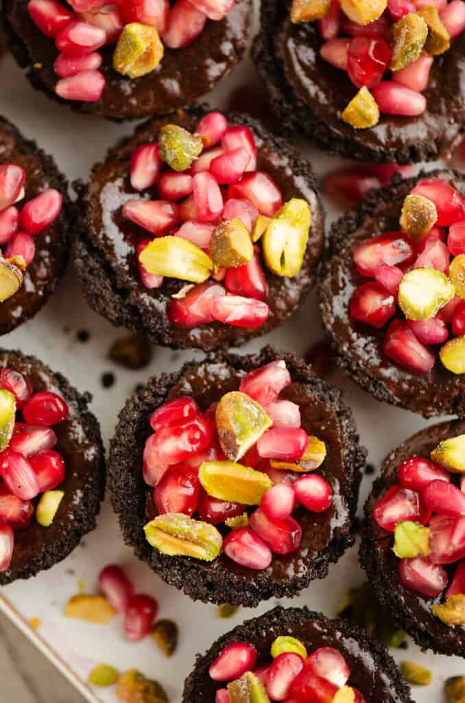 Mini Pomegranate Chocolate Tarts topped with pistachios