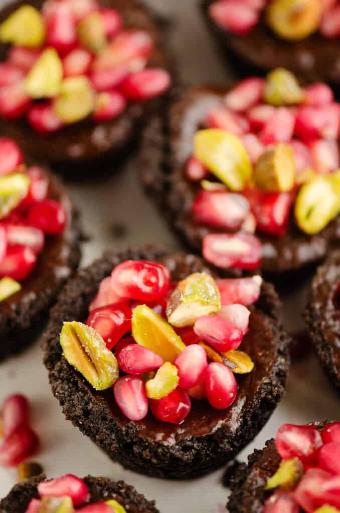 Mini Pomegranate Chocolate Tarts with pistachios on tray
