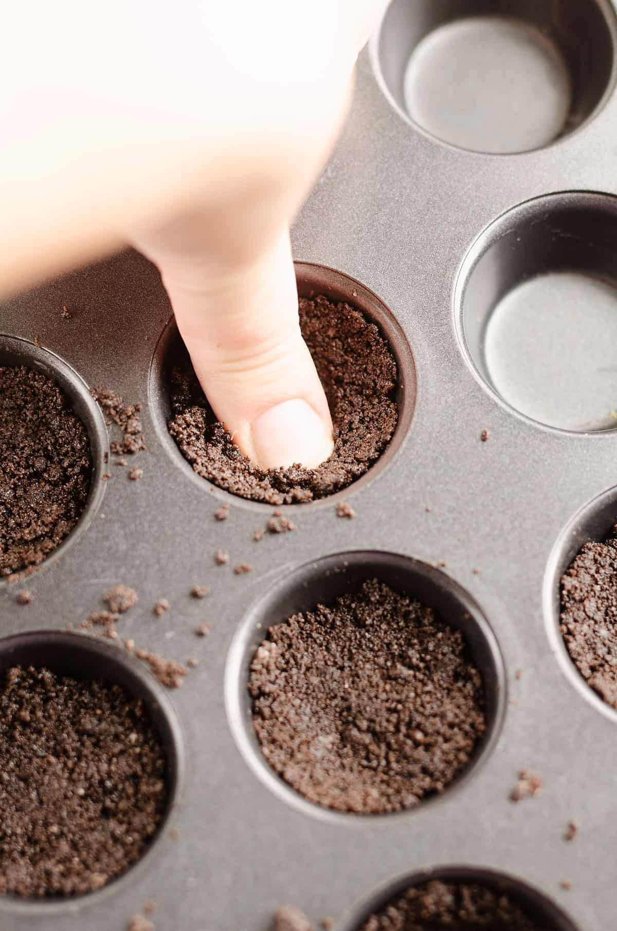 cookie crust scooped into muffin tins with finger