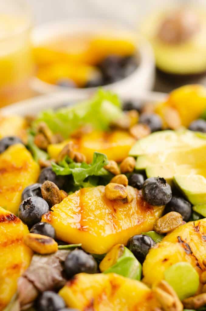 salad topped with pineapple, fruit and pistachio nuts