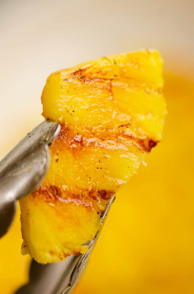 juicy grilled pineapple held in tongs