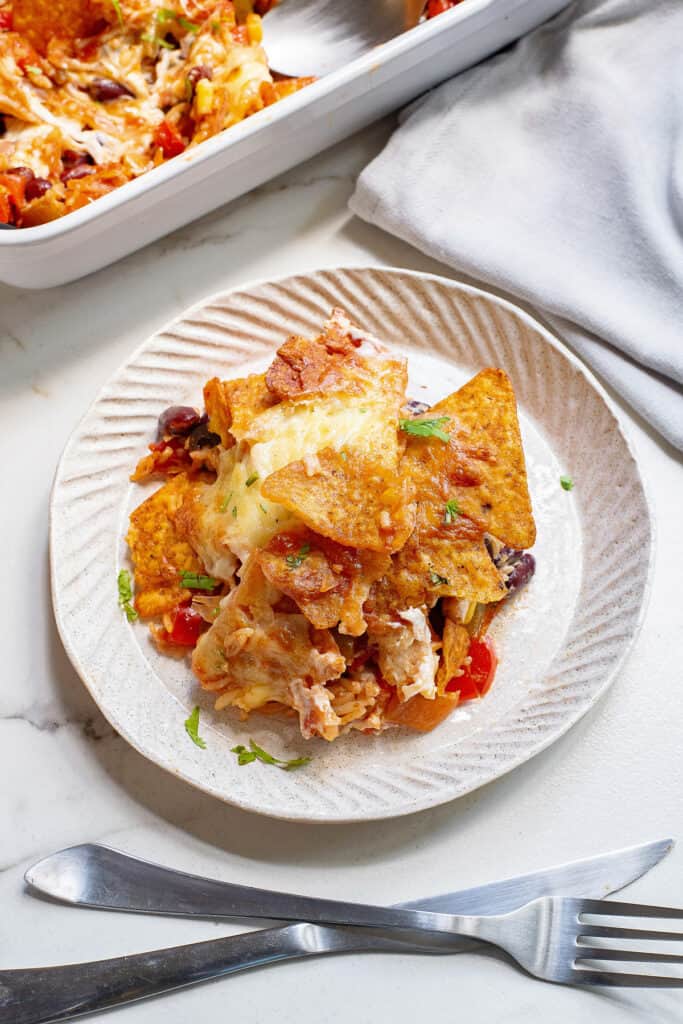 plate of cheesy Dorito casserole on table with fork and knife