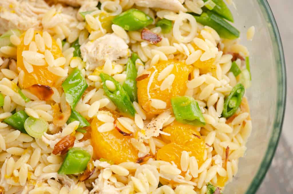 orange, pea, chicken and pasta salad in bowl