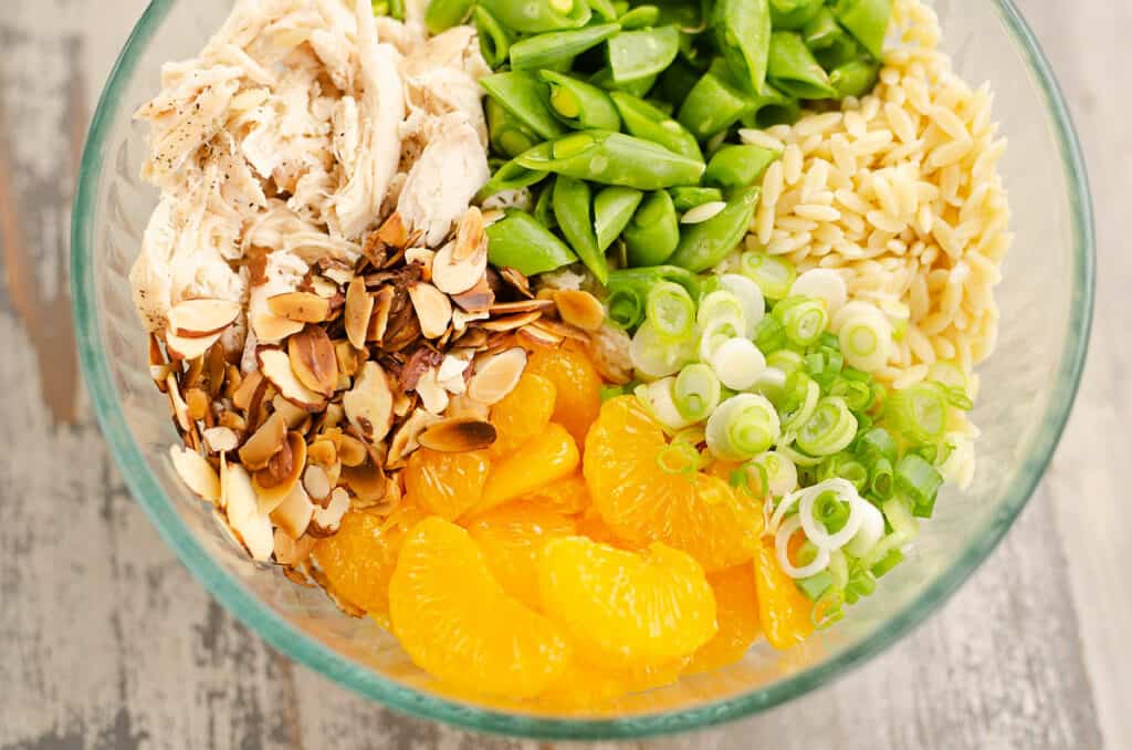 orzo pasta, oranges, onions, almonds and chicken in bowl