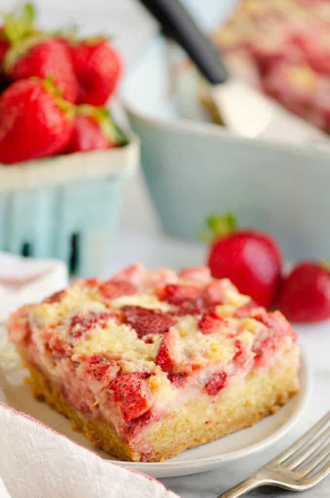 slice of strawberry custard bars on plate with strawberries in basket