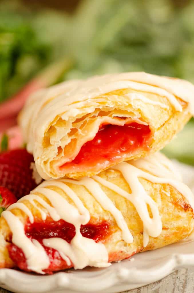 strawberry rhubarb turnovers stacked on plate and bite taken out