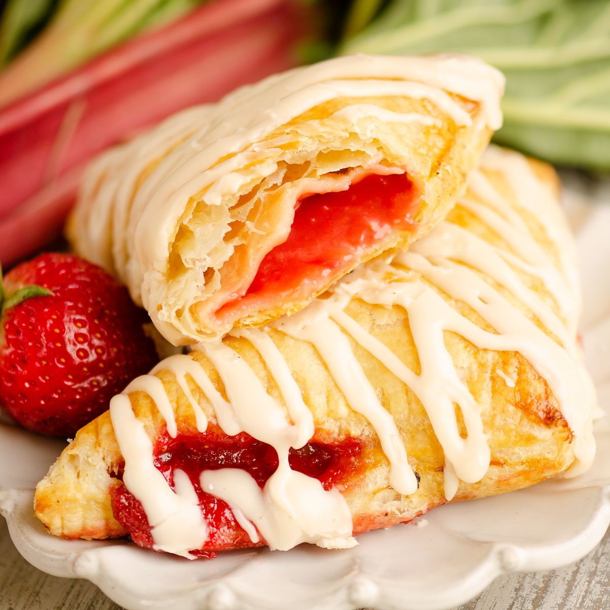 strawberry rhubarb turnovers drizzled with frosting on plate
