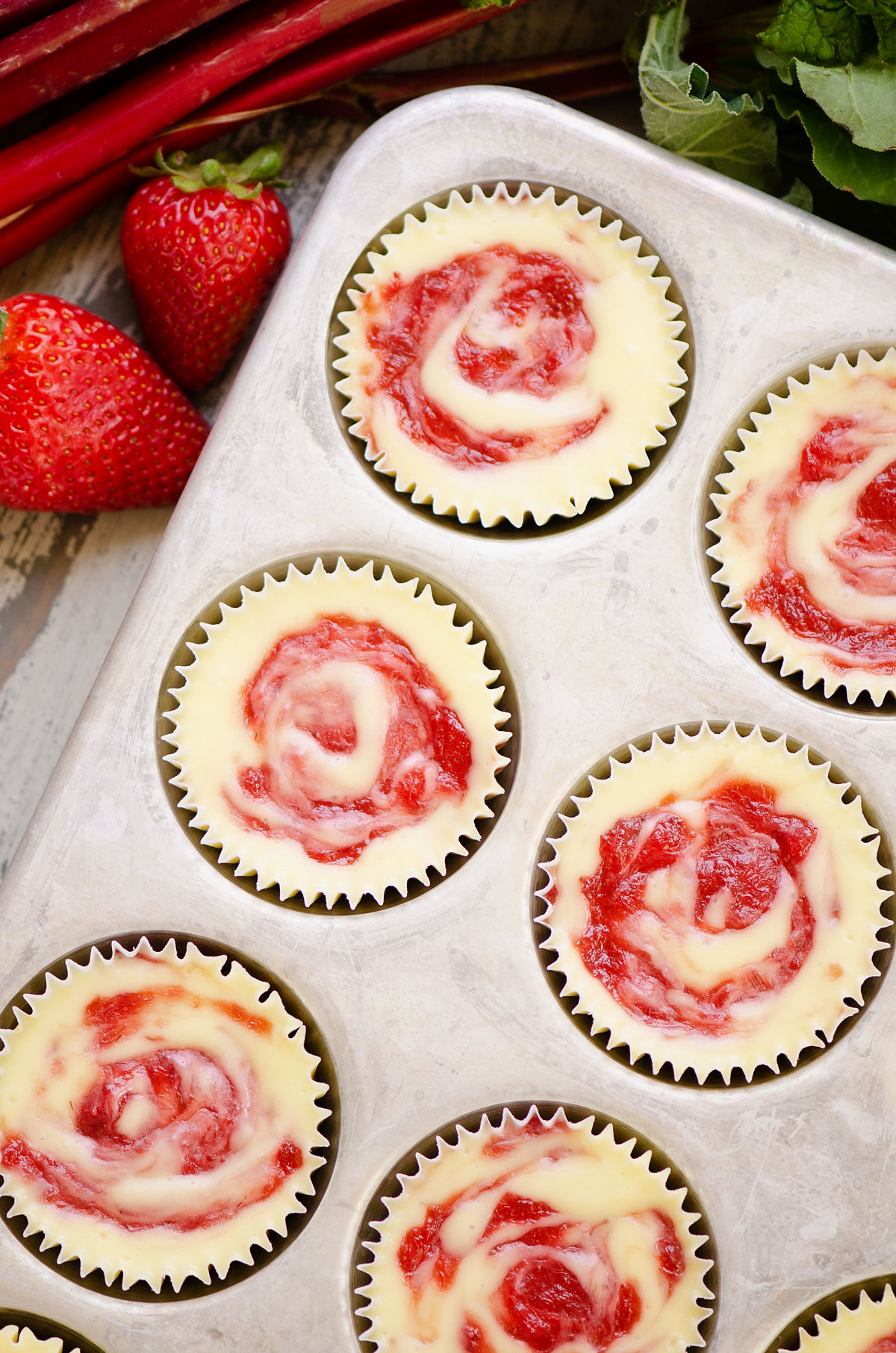 strawberry rhubarb mini cheesecakes in muffin tin