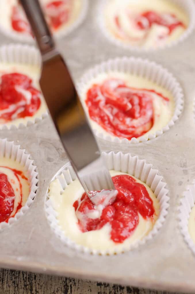 butter knife cutting rhubarb sauce into mini cheesecakes