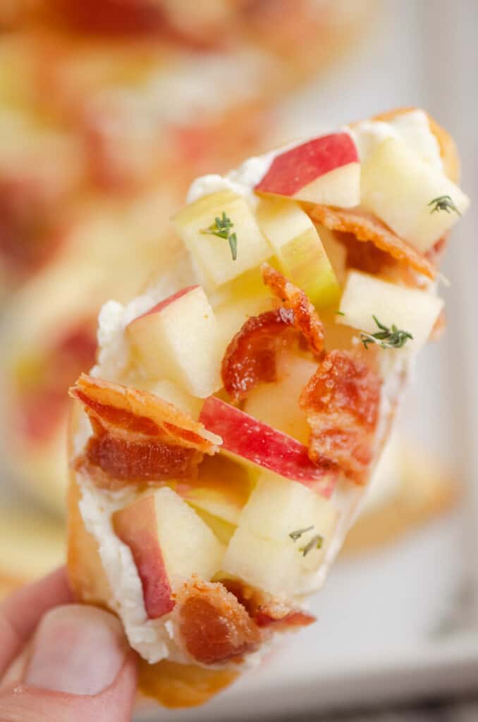 holding a apple bacon thyme crostini in hand