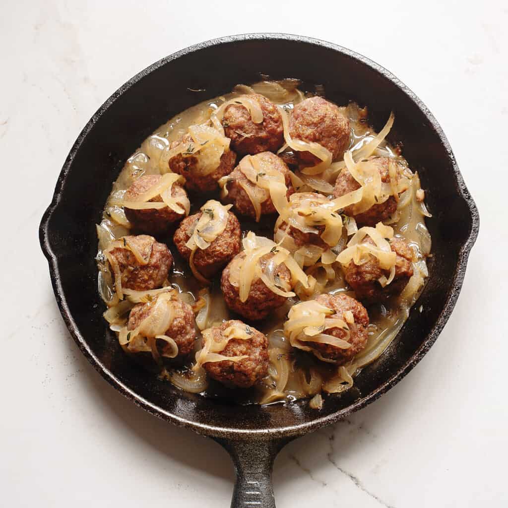 meatballs in skillet topped with onions