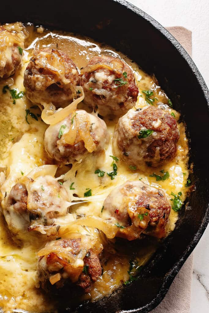 Cheesy French Onion Meatballs topped with thyme in skillet