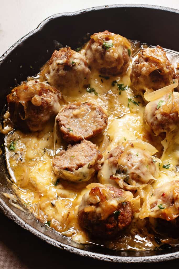 Sliced French Onion Meatballs in skillet with cheese and sauce