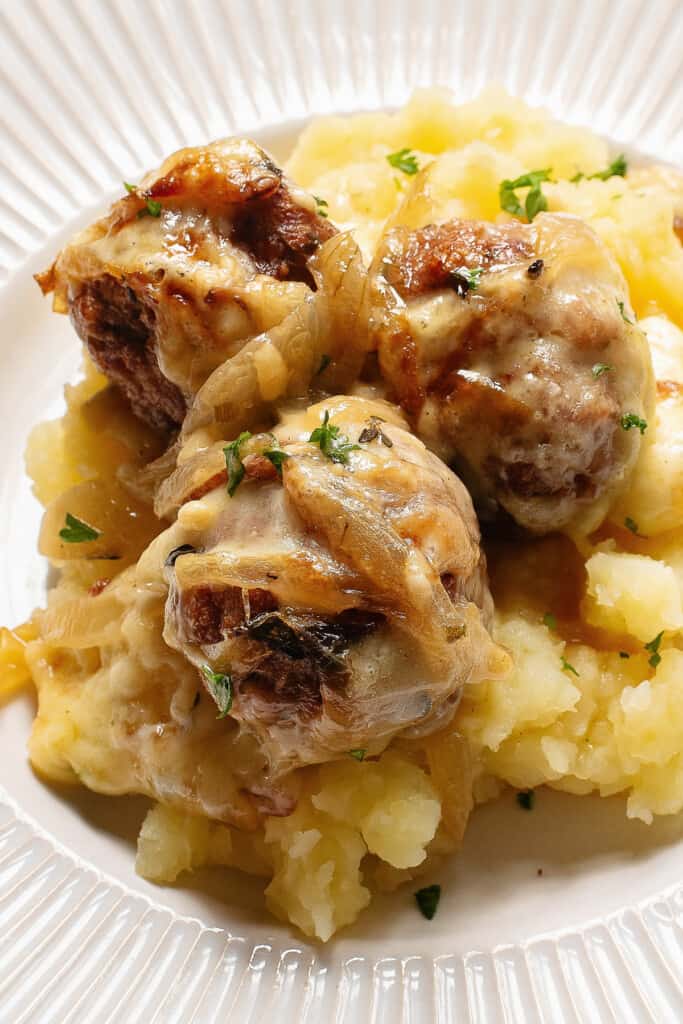 French onion meatballs over mashed potatoes on plate