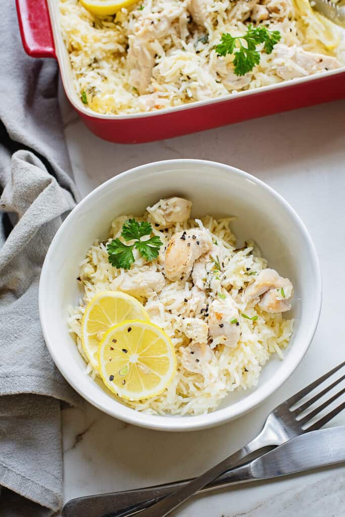 bowl of fluffy rice with lemon slices, chicken and parsley on table with fork
