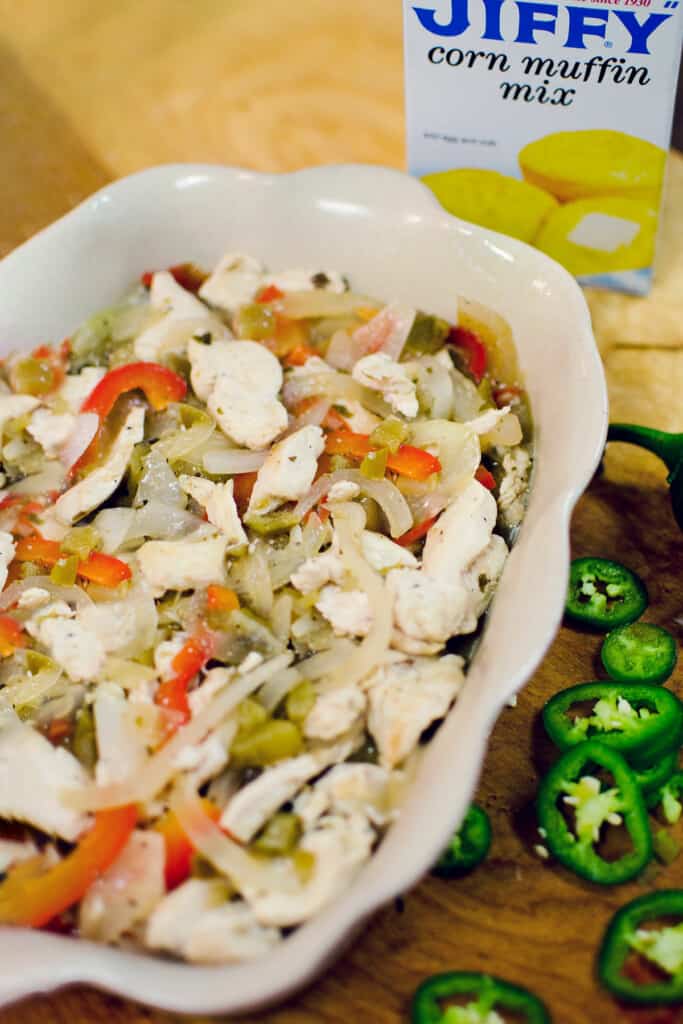 chicken, peppers and onions in casserole pan with box of Jiffy cornbread mix