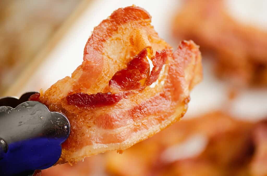 crispy bacon in tongs