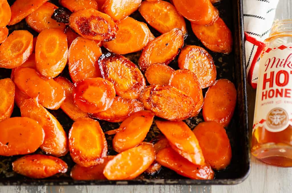 pan of roasted carrots with bottle of hot honey