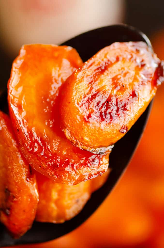 close up of caramelized hot honey roasted carrot on spoon