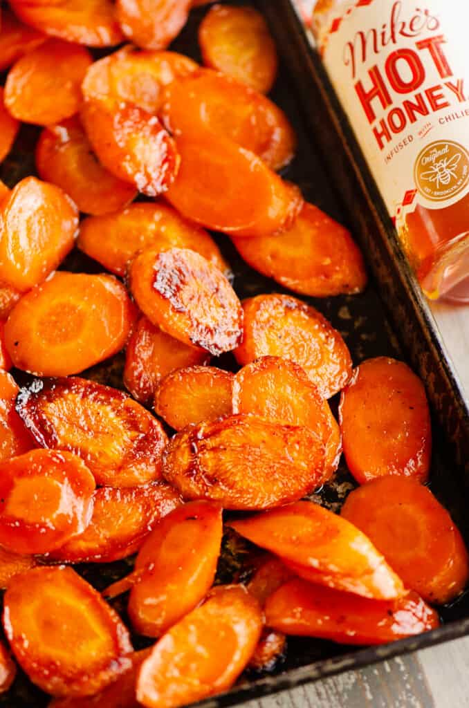 pan of roasted carrots by bottle of hot honey
