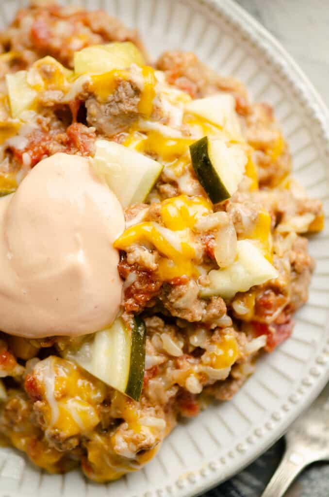 Pressure Cooker Cheeseburger Rice casserole on plate topped with pickles and special sauce