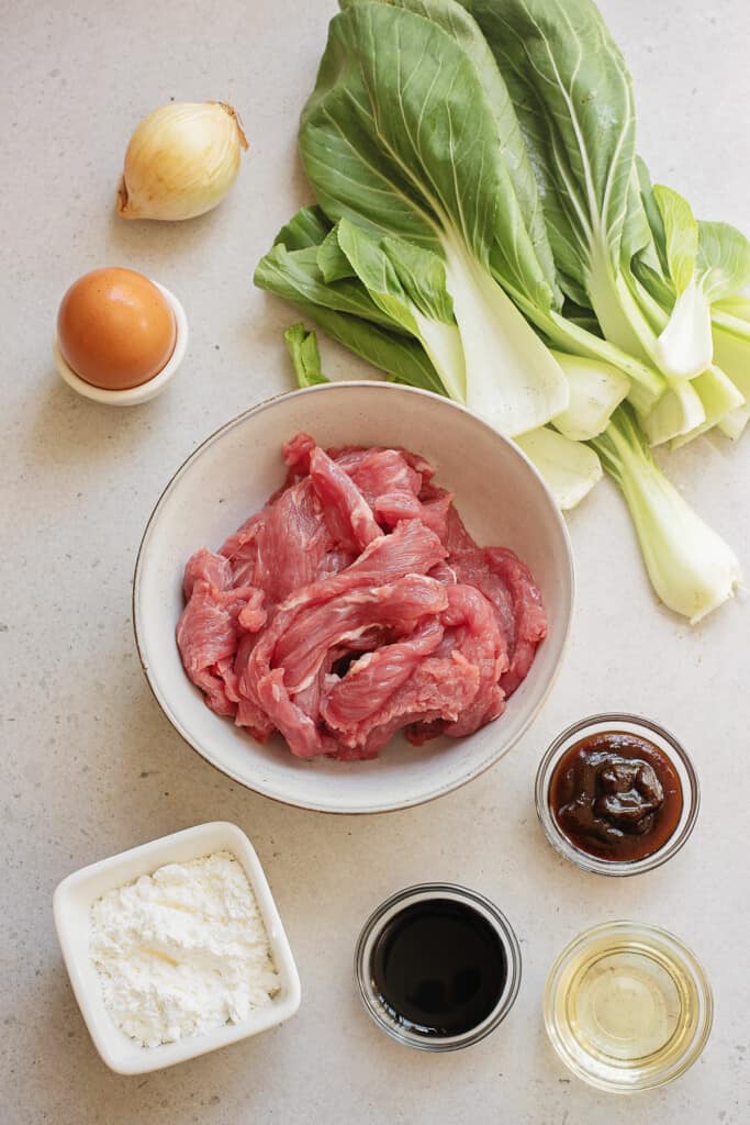 beef, Bok choy, egg, onion, cornstarch, oyster sauce and soy sauce on table