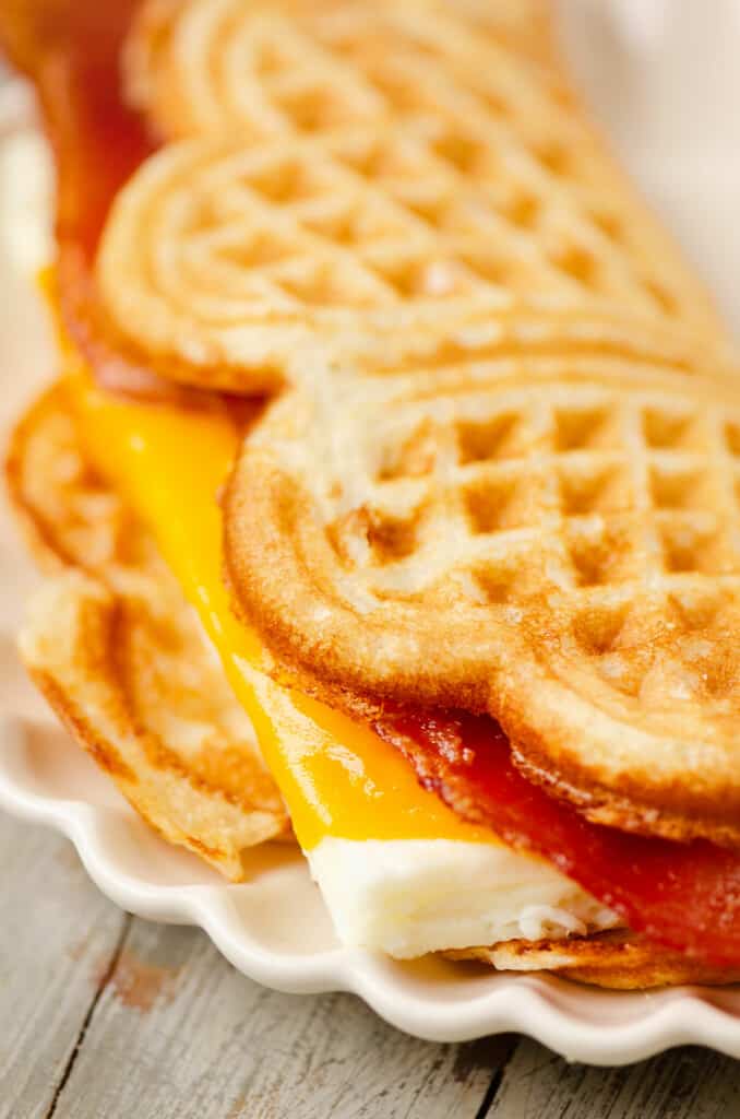 waffle breakfast sandwich filled with cheesy eggs on plate