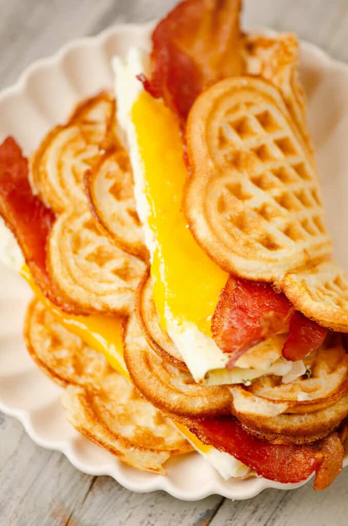 waffle breakfast sandwiches stacked on fluted plate