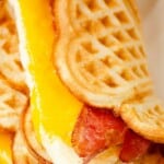 cheese egg and bacon waffle breakfast sandwiches stacked