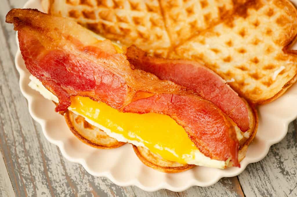 thin waffle topped with cheesy eggs and bacon