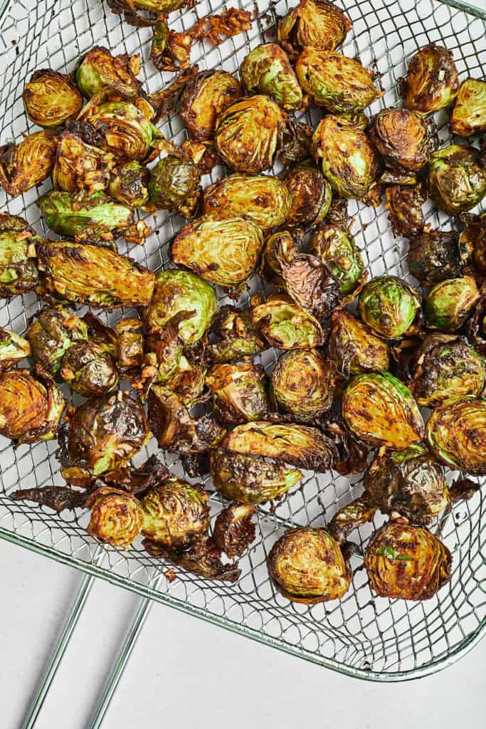 maple dijon and pecan brussels sprouts in bowl on cutting board in air fryer basket