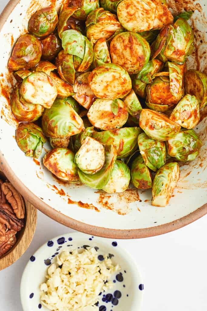 brussels sprouts tossed in paprika seasoning in large bowl